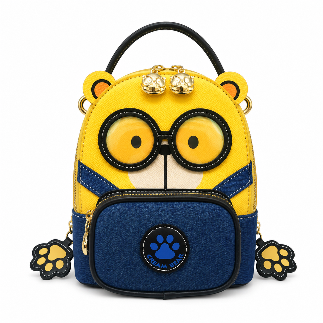 Yellow and blue cartoon bear kids backpack with oversized glasses design, front zip pocket, paw-shaped charms, and top handle on a white studio background.
