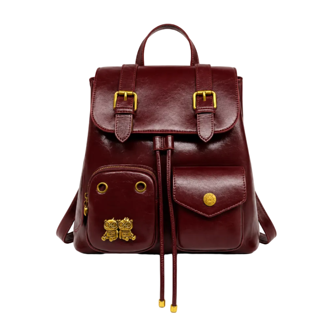 Burgundy vintage-style women's backpack with dual front pockets, buckle flap closure, top handle, and gold-tone hardware.
