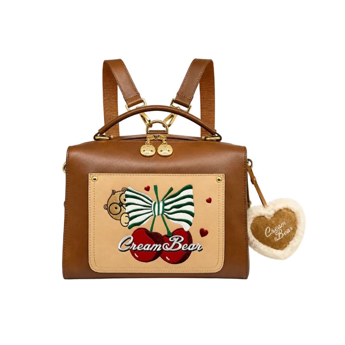 Brown convertible backpack with embroidered bow and cherry design, decorative heart plush charm, and top handle on a white background.