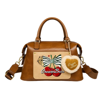 Brown Cream Bear Boston handbag with embroidered bow and cherry design, plush heart charm, dual top handles, detachable shoulder strap, and white studio background.