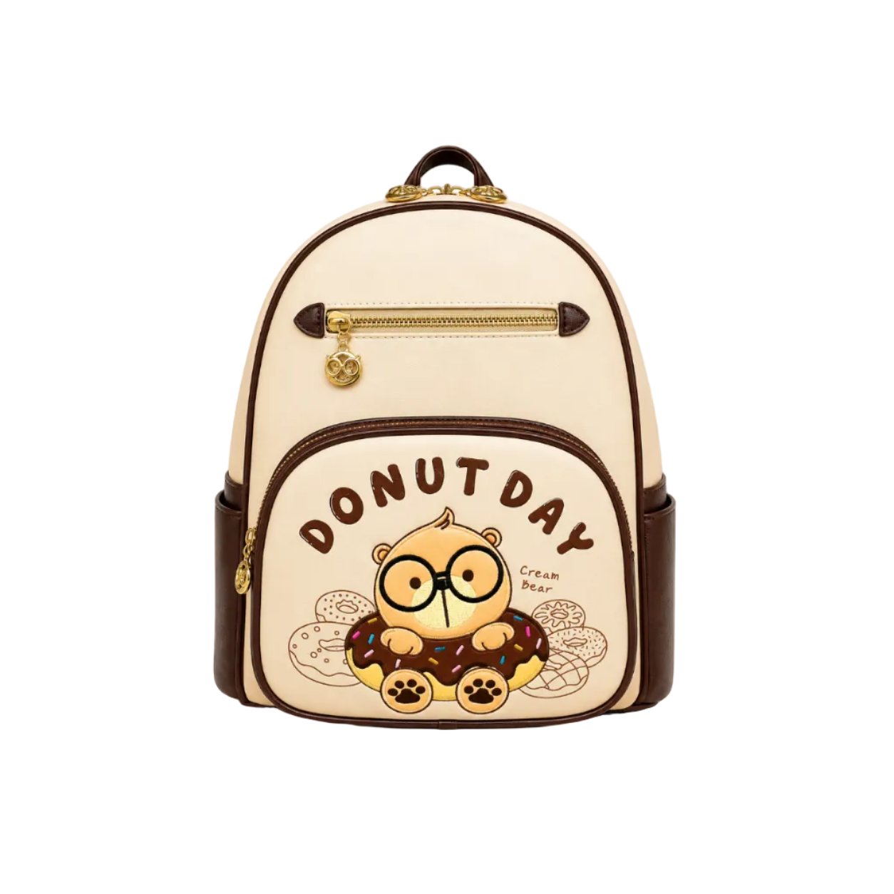 Cream backpack with brown trim featuring a Cream Bear donut embroidery, front zip pocket, and gold-tone hardware.