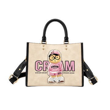 Beige Cream Bear fashion tote bag with black handles, pink bear graphic, gold hardware, and detachable shoulder strap on a white studio background.