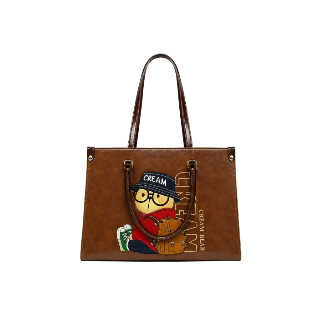 Brown Cream Bear fashion tote bag with cartoon traveler bear graphic, long shoulder handles, and white studio background.