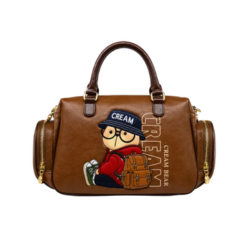 Brown Cream Bear Boston handbag with embroidered bear wearing a red hoodie, dual top handles, side zip pockets, gold-tone hardware, and white studio background.