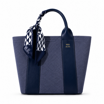 MISS ALITA blue canvas tote handbag with leather trim, blue and white silk scarf handle, structured design, and gold logo on a white background.