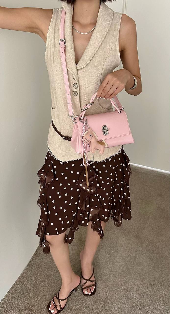 Pink structured top handle handbag with silver twist-lock closure and decorative pink horse charm on a white studio background.