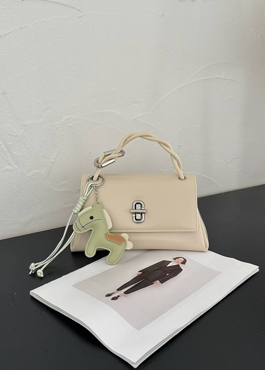 Off White structured top handle handbag with silver twist-lock closure and decorative green horse charm on a white studio background.